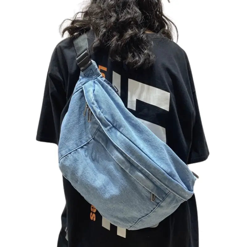 Femme qui porte en bandoulière un grand sac banane en jean bleu clair __switch:Bleu